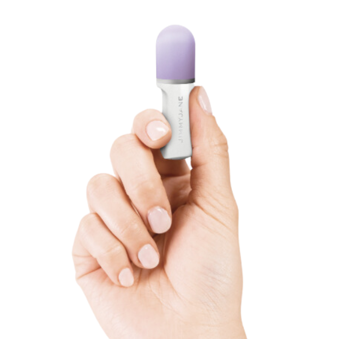 A hand holds the JIMMYJANE® Hello Touch® Pro, a small capsule-shaped object with an ergonomic design, against a white background.