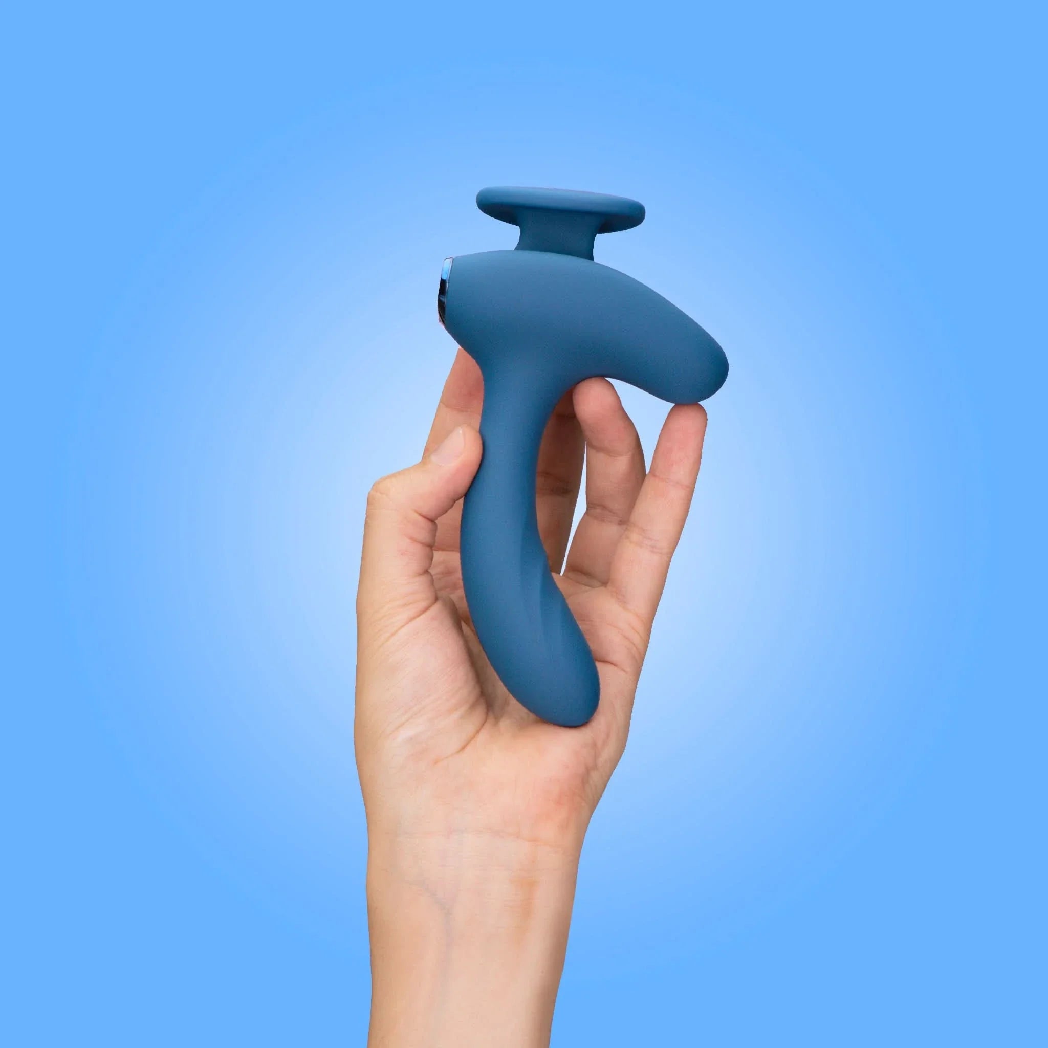 A hand holds the JIMMYJANE® Solis™ Kyrios, a blue, ergonomically-shaped dual motor prostate massager, against a light blue background.