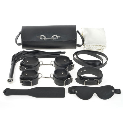 The JIMMYJANE® 7-Piece Bondage Set, made of black vegan leather, includes cuffs, paddle, whip, blindfold, collar, leash, carrying bag, and a white cloth—ideal for elevating any couple’s experience.