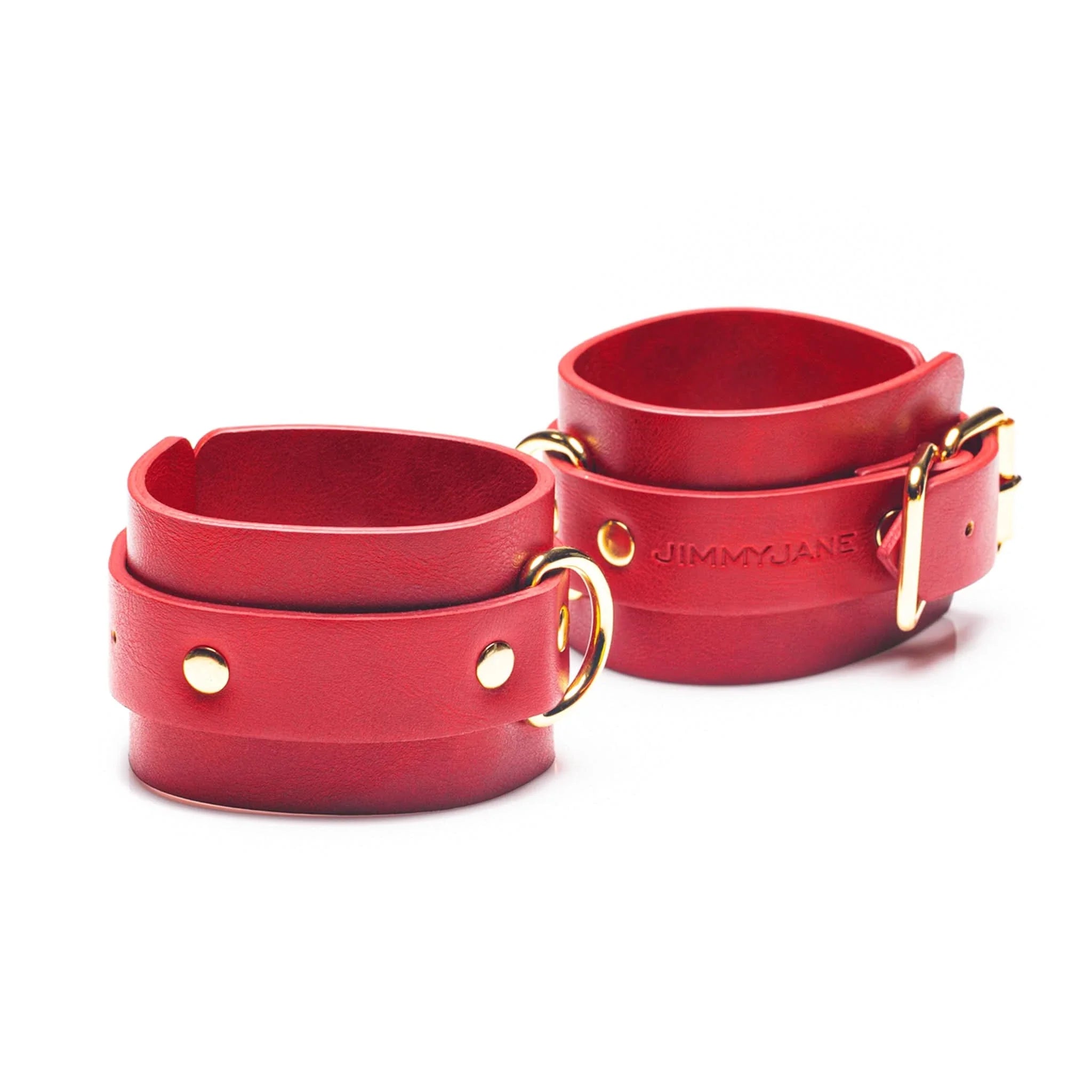The JIMMYJANE® 4-Piece Bondage Set features red vegan leather wrist cuffs with gold buckles and studs, ideal for couples play, displayed on a white background.