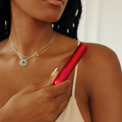 A woman in a beige top holds the JIMMYJANE® Chroma™ bullet vibrator, known for its sleek, waterproof design, against her collarbone.