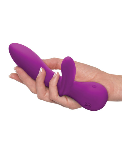 A hand holds the JIMMYJANE® G Rabbit, a purple silicone vibrator featuring a curved shaft for G-spot stimulation and an external clitoral stimulator.